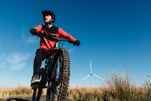 A Man In A Red And Black Jersey On A Mountain Bike At A Wind Farm In Scotland