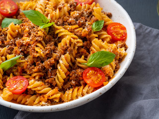 Bolognese pasta. Fusilli with tomato sauce, ground minced beef, basil leaves. Traditional italian cuisine. Side view