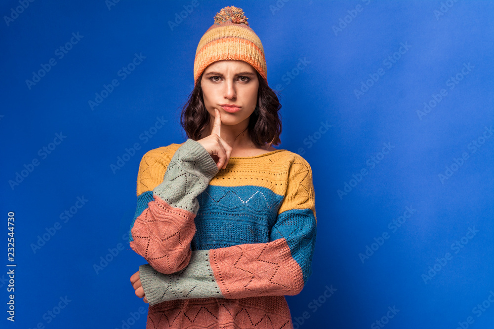 thoughtful girl in a knitted sweater and a yellow hat  - obrazy, fototapety, plakaty 