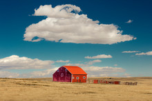 Red Barn In Field With Puffy Clouds In Remote Oklahoma