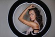 © Stocksy - Young attractive woman posing behind the selfie lamp