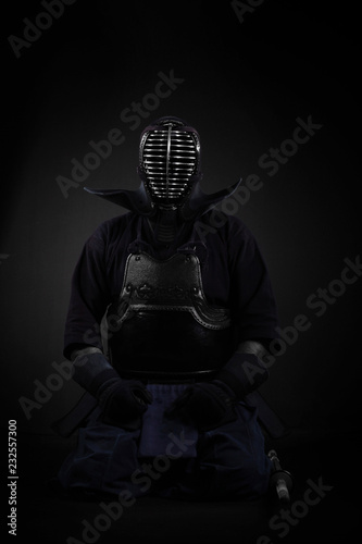 Plakaty Kendo  zawodnik-kendo-trzyma-i-trenuje-z-bambusowym-mieczem-w-studio-na-czarnym-tle