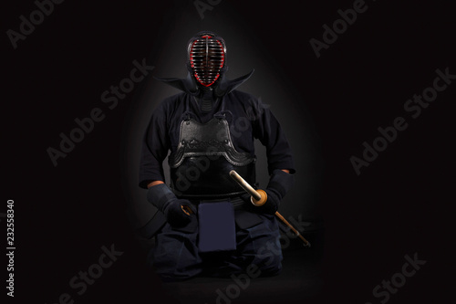 Dekoracja na wymiar  kendo-wojownik-trzyma-i-trenuje-z-bambusowym-mieczem-w-studio-na-czarnym-tle