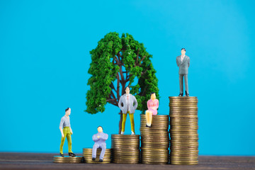 Figure miniature businessman or small people investor and office worker secretary standing on coin stack with little tree decoration, for money and financial business success concept.