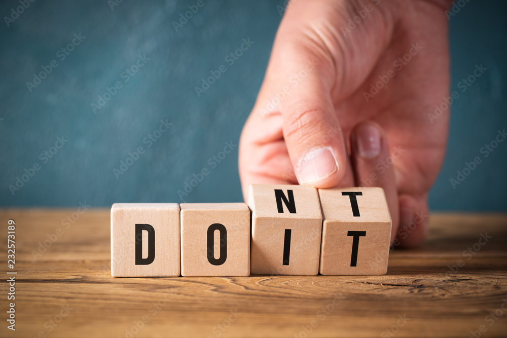 Hand turns two cubes, changing the word "don't" to "do it"  - obrazy, fototapety, plakaty 
