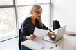 © Stocksy - Senior businesswoman working on laptop at office.
