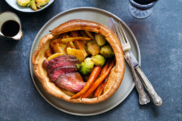 Canvas Print - Roast dinner with beef, carrots, brussel sprouts in giant yorkshire pudding