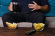 overeating, sedentary lifestyle, bad habits, food addiction, eating disorders. fat overweight man sitting on the sofa with junk food and tv remote. depression, laziness problem eating
