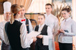 © davit85 - restaurant manager and his staff in kitchen. interacting to head chef in commercial kitchen.