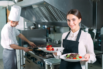 restaurant kitchen. Waiter with a ready-made dish Foie Gras posing in the background of the kitchen.