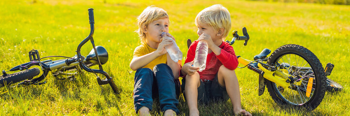 Wall Mural - Two little boys drink water in the park after riding a bike BANNER, LONG FORMAT