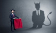 Businessman standing with red cloth in his hand and devil shadow on the background
