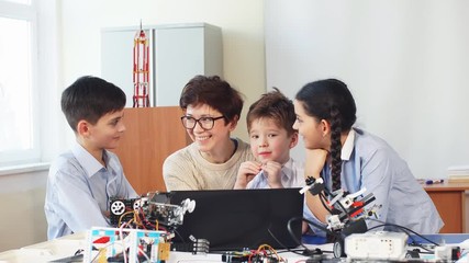 curious clever pupils with the help of their female teacher doing a group project programming homema