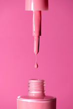 Pink shade nail polish dripping from applicator