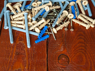 Screws and plastic dowels on a wooden background. Selective focus.