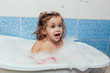© Andrii - Fun cheerful happy toddler baby taking a bath playing with foam bubbles. Little child in a bathtub. Smiling kid in bathroom on blue background. Hygiene and health care.