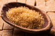 In the foreground crystals of raw cane sugar in the wooden spoon