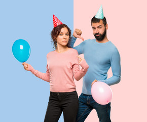 couple with balloons and birthday hats proud and self-satisfied in love yourself concept on pink and blue background