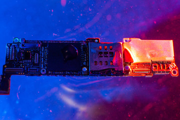 The main board from the phone, in the water with blue and red lights in the water