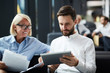 © pressmaster - Young serious businessman showing his mature colleague online data in touchpad