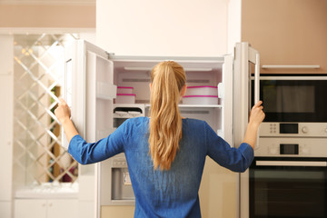 Sticker - Young woman choosing food in refrigerator at home