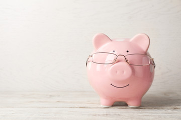  Piggy bank with glasses on light table. Space for text