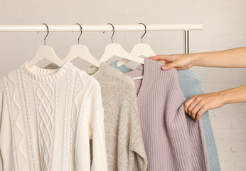 Wall Mural - Woman choosing sweater on rack against brick wall