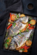 Two fresh barbecue gilthead seabreams with vegetable and fruits as top view in an old metal sheet