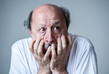 Close up of scared and shocked senior man gesturing in fear with hands and face