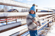 © Виталий Сова - A young woman in a blue knitting hat, white fur coat  enjoys winter nature, posing around fence, walking on  village around blue sky in winter frosty day.