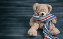 Cute Teddy Bear With Colorful Scarf Sitting On Blue Wooden Background