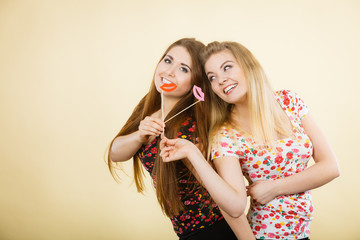 Canvas Print - Two happy women holding fake lips on stick