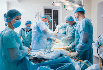 Wall Mural - Process of gynecological surgery operation using laparoscopic equipment. Group of surgeons in operating room with surgery equipment