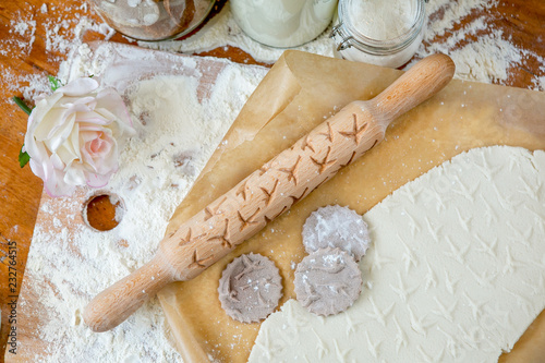 Fotografie, Obraz Rolling pin with a pattern on a wooden decorated table covered with baked flour