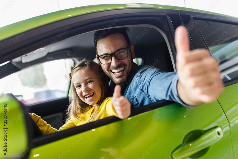 Father and daughter buying a new car at the car showroom.