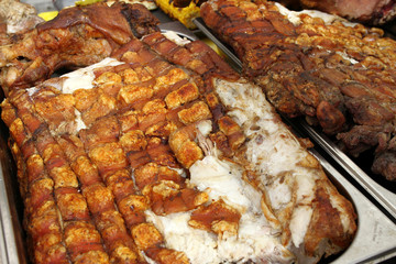 Big piece of roasted pig meat with cuuting knifes. Swine baked on a rotating grill -cheverme. fast food and fat concept. pieces of meat prepare for eating. Christmas festival market.