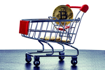 Golden bitcoin cryptocurrency in a shopping cart on a black shiny surface