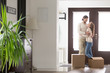 © fizkes - Young married satisfied couple standing in hallway, arrive at new house with cardboard boxes. Glad wife and husband hugging feel happy buying new dwelling. Relocation, moving mortgage or loan concept