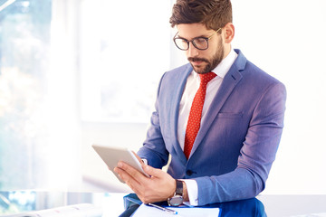 Confident busienessman with digital tablet sitting at office desk