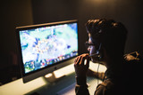 Fototapeta Kwiaty - Young indian man with headphones playing video game in dark room