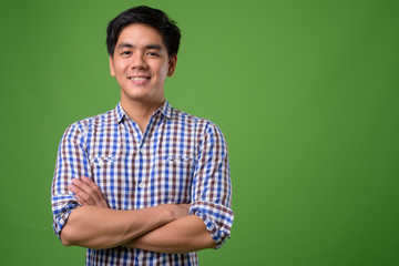 Young handsome Filipino man against green background