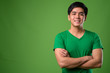 Young handsome Filipino man against green background