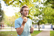 © New Africa - Young man blowing soap bubbles in park