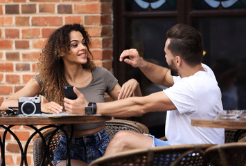 Poster - Lovely young couple looking at smart phone at cafe