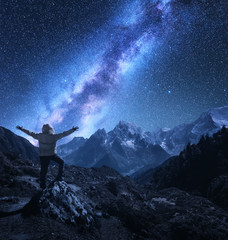Wall Mural - Silhouette of a standing man with raised up arms on the stone, mountains and starry sky with Milky Way at night in Nepal. Sky with stars. Travel. landscape with mountain ridge and milky way. Space