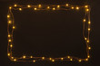 Christmas lights garland border over black background. Flat lay, copy space.