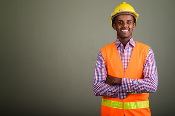 Wall Mural - Young handsome African man construction worker against colored b