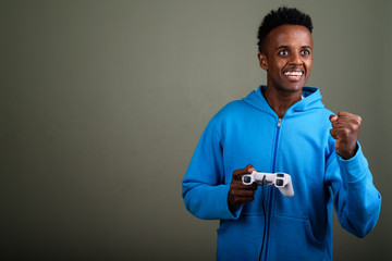 Wall Mural - Young handsome African man wearing hoodie against colored backgr