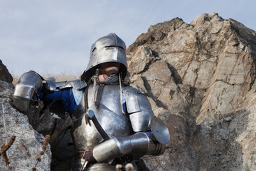 Knight with a sword and in medieval armor on the background of granite stone