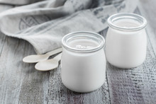 Greek Yogurt In A Glass Jars With Wooden Spoons On Wooden Background. Healhty Breakfast Food. Copy Space